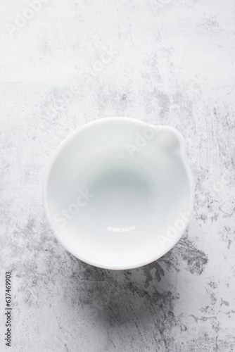 Top view of ceramic bowl with spout on a marble table, white ceramic mixing bowl