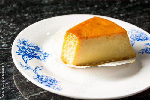 pudding or pudim slice, on a white plate and black background. gourmet or homemade delicious pudding also known as flan photo