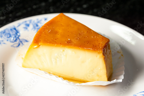 pudding or pudim slice, on a white plate and black background. gourmet or homemade delicious pudding also known as flan photo
