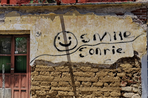 Smile. Sonrie. Graffiti de smiley avec texte anglais et espagnol (sourire, souries) sur un vieux mur dans la rue. Mexique.