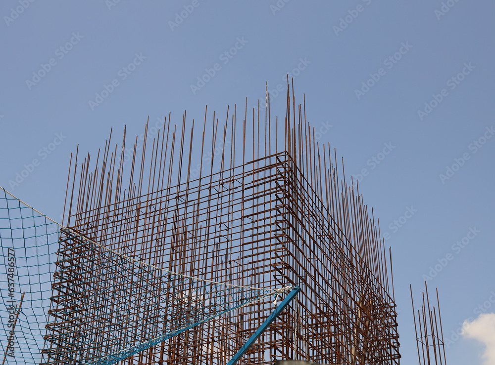 view of Construction site foundation Reinforced Concrete With Steel Rebar against blue sky. Rebar steel for concrete columns - construction site. metal reabars around at building site. view of Construction site foundation Reinforced Concrete With Steel Rebar against blue sky. Rebar steel for concrete columns - construction site. metal reabars around at building site.