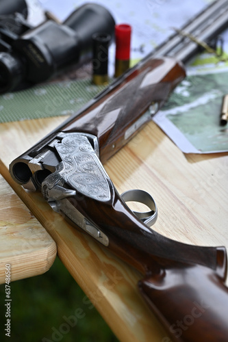 The hunting rifle,binoculars,ammunition on a wooden table