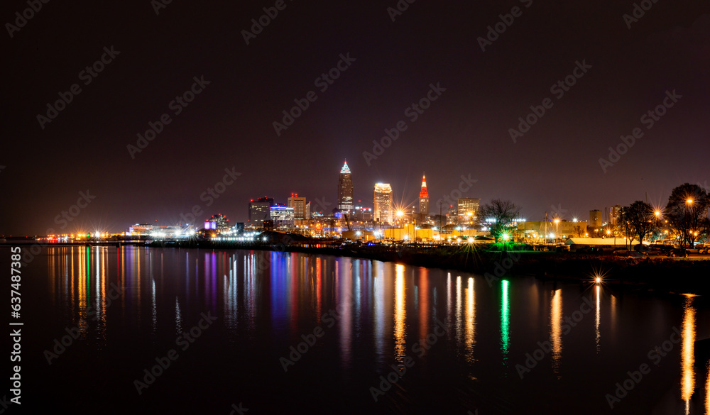 A colorful nighttime cityscape of Clevland, Ohio with relectiontions in the still water of Lake Erie