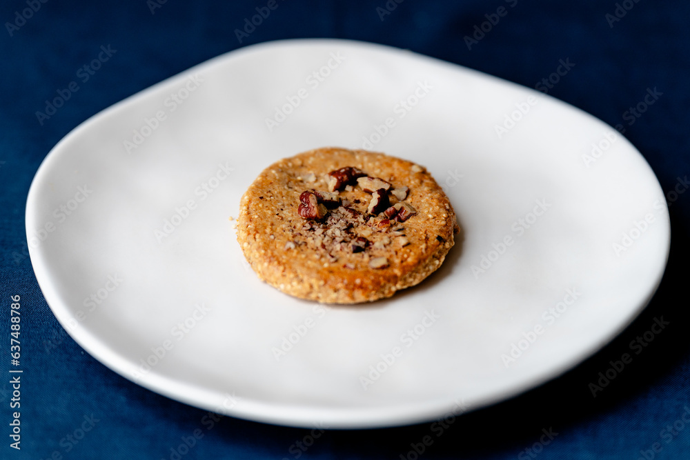 Walnut cookie on a white plate - side view Walnut cookie on a white plate - side view