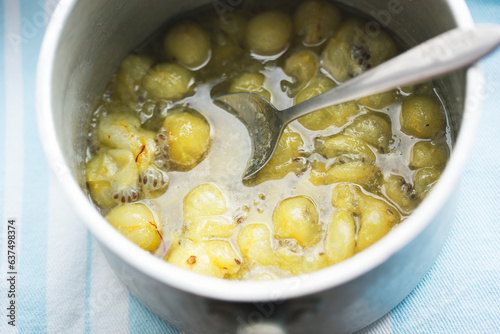 Boiling gooseberry with safron and honey. Making gooseberry compote 