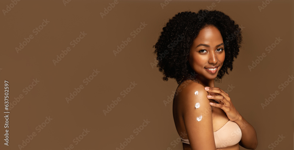 Happy pretty young black woman applying cream on shoulder, banner Happy pretty young black woman applying cream on shoulder, banner