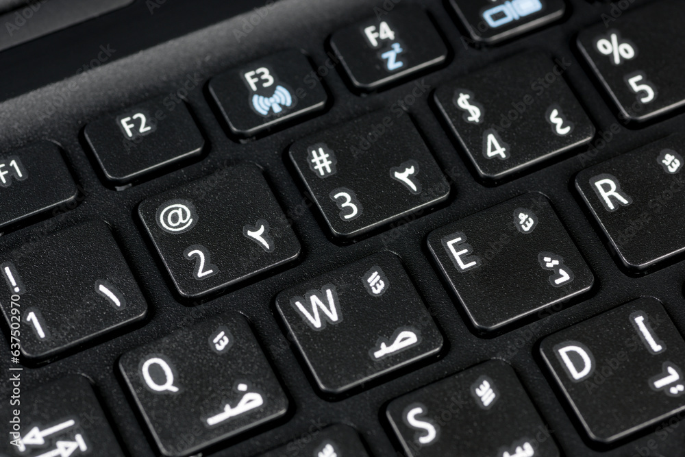 Close up of a QWERTY keyboard english and arabic with letters, figures and symbols, focus on symbol @ Close up of a QWERTY keyboard english and arabic with letters, figures and symbols, focus on symbol @