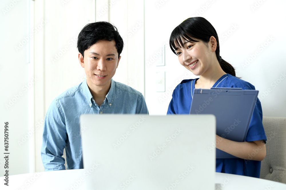 PCの前で話す女性の医療従事者と男性患者
