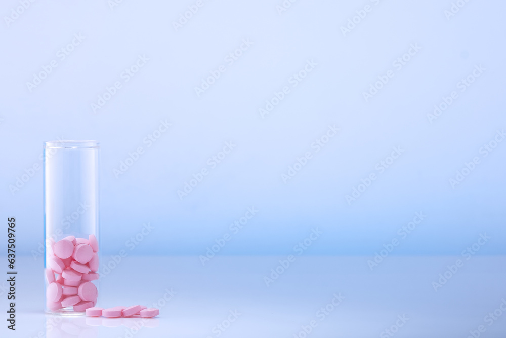 Pink pills in a glass bottle on a blue background. Health care, medical pills and nutritional supplements Pink pills in a glass bottle on a blue background. Health care, medical pills and nutritional supplements