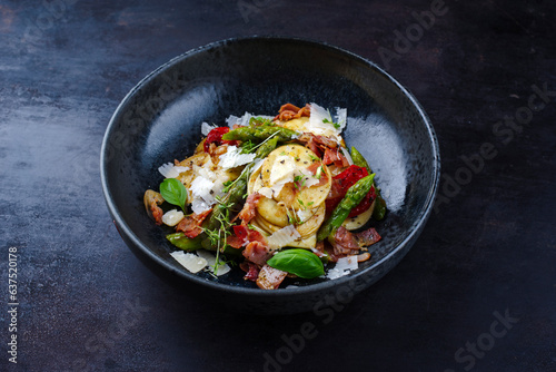 Green glazed asparagus with fried prosciutto ham, croxetti pasta and parmesan cheese served as close-up on a design plate with text space 