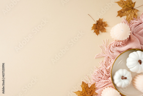 Fototapeta Naklejka Na Ścianę i Meble -  Immerse yourself in the tranquil and snug comforts of fall at home. Top view photo of warm pink plaid, pumpkins, candles, autumn maple leaves on pastel beige background with empty space for ad or text