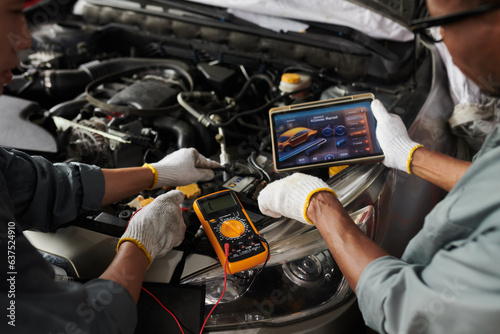 Closeup image of mechanics using application on tablet computer when checking car engine