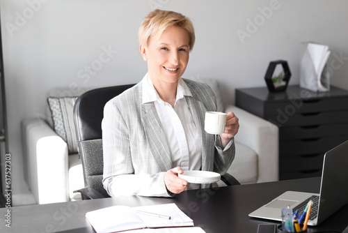Mature businesswoman drinki...