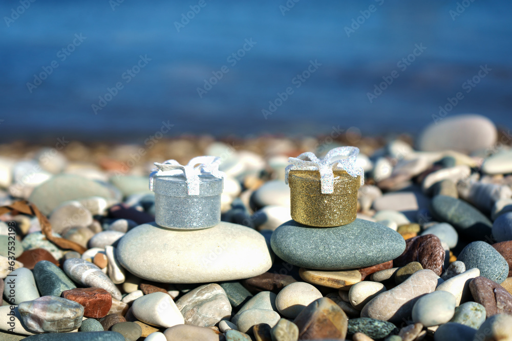 Two ring boxes placed on a pebble against the backdrop of the sea