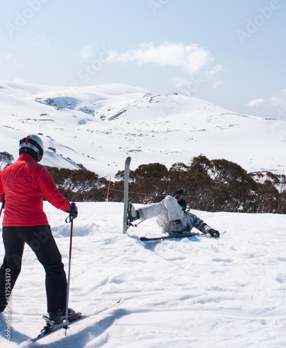 An accident on skis, female skier in the foreground trying to help another skier in Charlotte's Pass ski resort in Australia