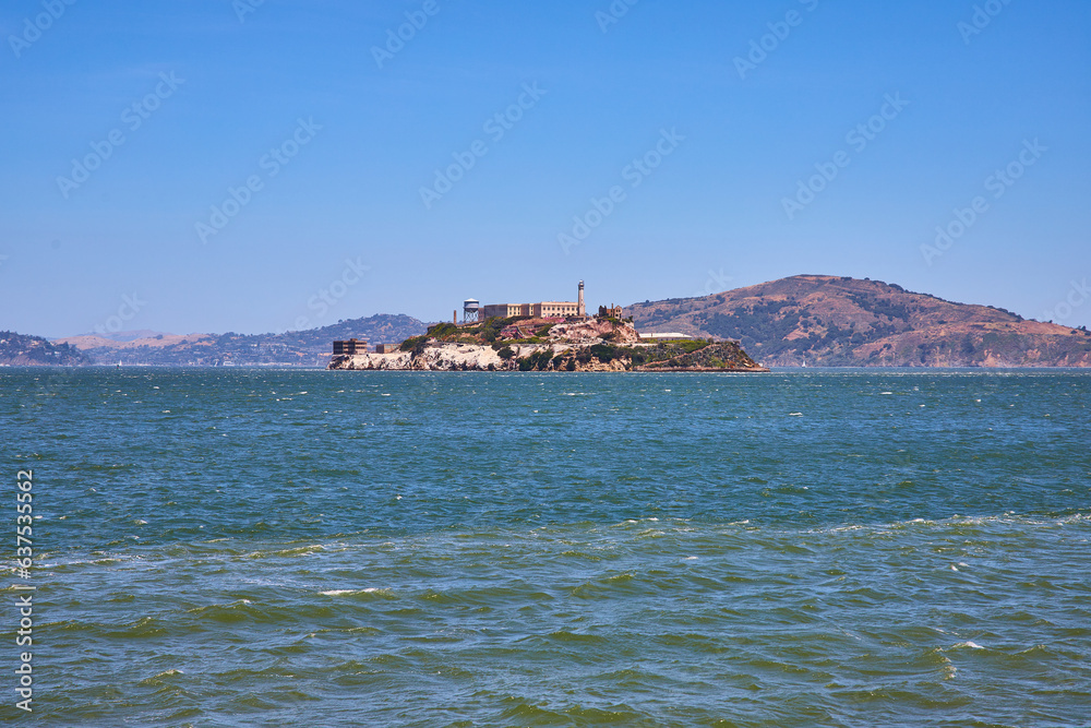 Choppy waters on bay area around full Alcatraz Island and mountainous hills in distance