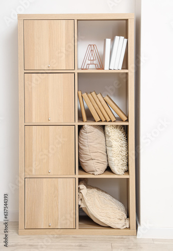 Wooden bookcase with pillows and decor in light room