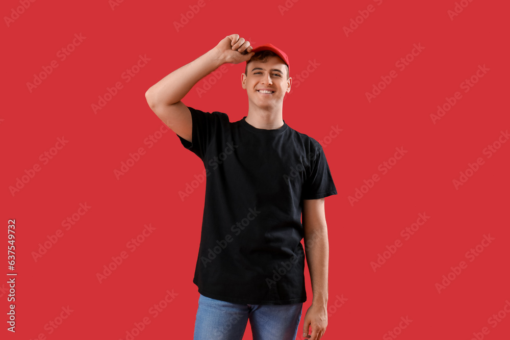 Young man in black t-shirt and cap on red background Young man in black t-shirt and cap on red background