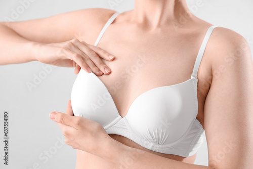 Young woman in bra on light background, closeup. Breast cancer awareness concept