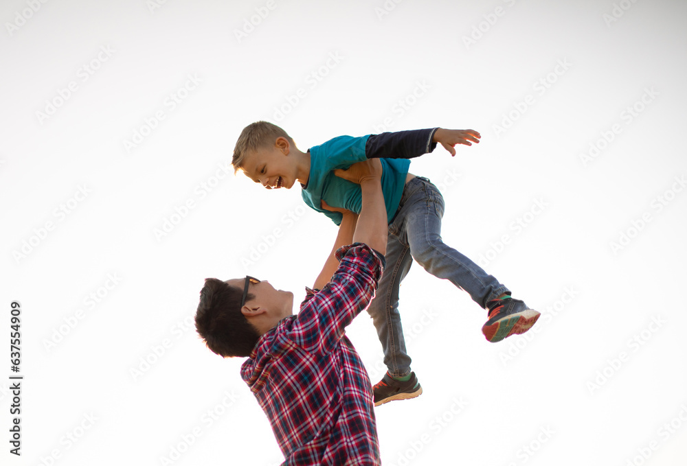 Father lifting his son up in the air playing together bonding outdoors 