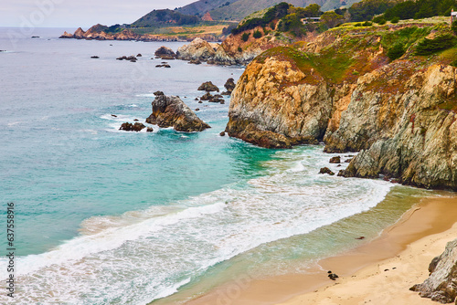 Beautiful ocean waves crashing against shoreline with yellow faced cliffs and crags photo