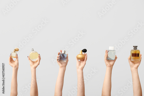 Female hands holding different perfumes on grey background