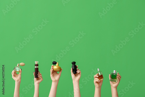 Female hands holding different perfumes on green background