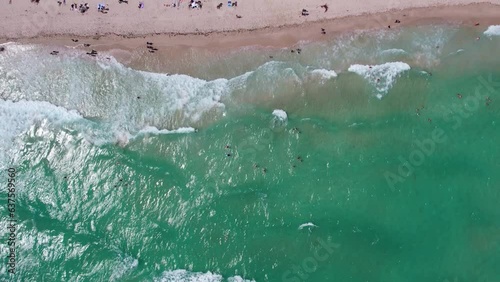 A drone flying directly over the beach in Miami with many people