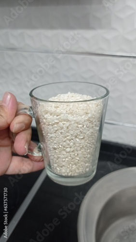 hand holding a cup of rice for cooking sushi or aasian food photo