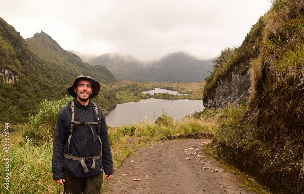 Hiker smailing at camera with mountains and lagoons landscape in National Park in Ecuador