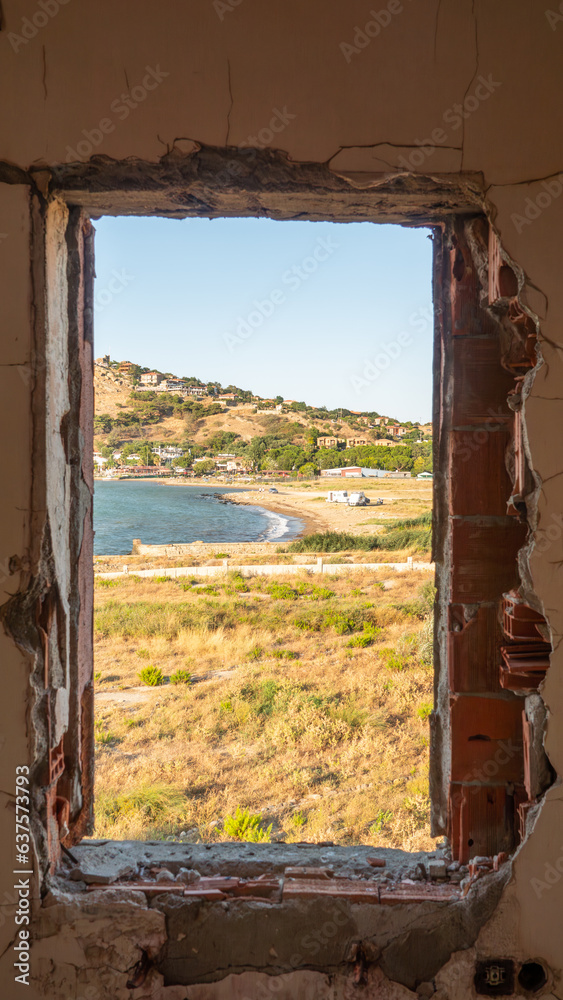 Window to the sea in an abandoned house across to Kalekoy sea town. The Aegean sea town view from window. Gokceada, Imbros island, Canakkale. Window to the sea in an abandoned house across to Kalekoy sea town. The Aegean sea town view from window. Gokceada, Imbros island, Canakkale.