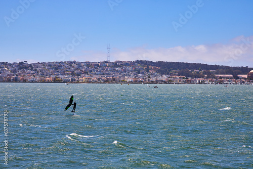 Photography Man sailboarding on choppy bay waters with distant San Francisco shoreline