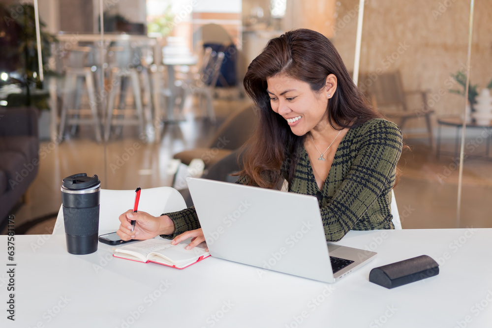 Cheerful female office worker writing in planner Cheerful female office worker writing in planner