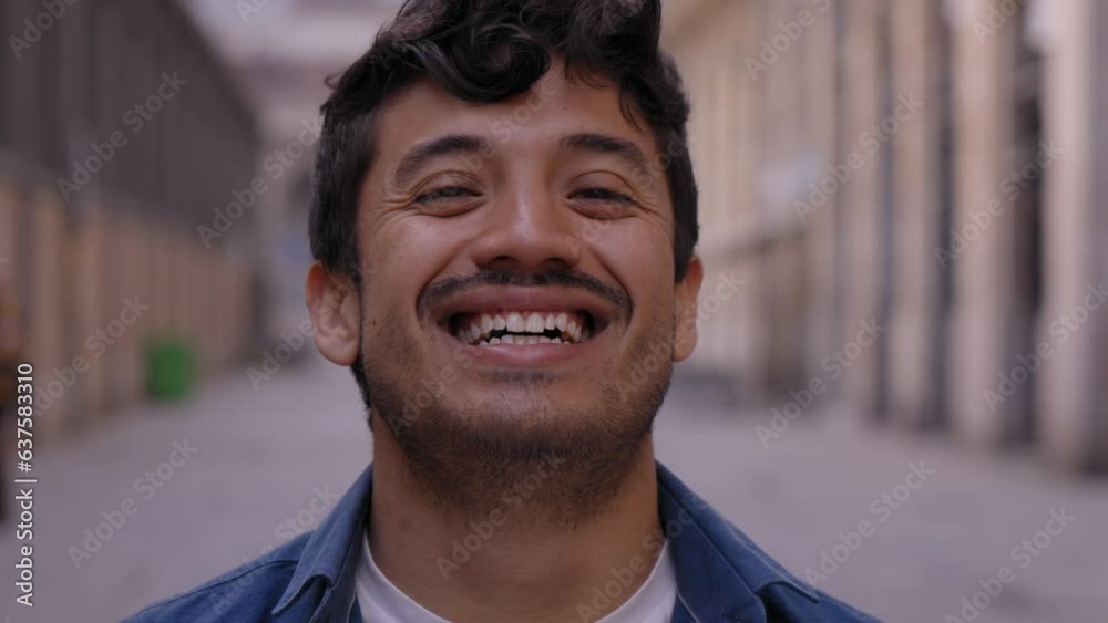 Close up face of happy young Latin man happy smiling on street. Male people with cheerful expression looking at camera in open air. Nice boy posing for photo outdoor. Close up face of happy young Latin man happy smiling on street. Male people with cheerful expression looking at camera in open air. Nice boy posing for photo outdoor.