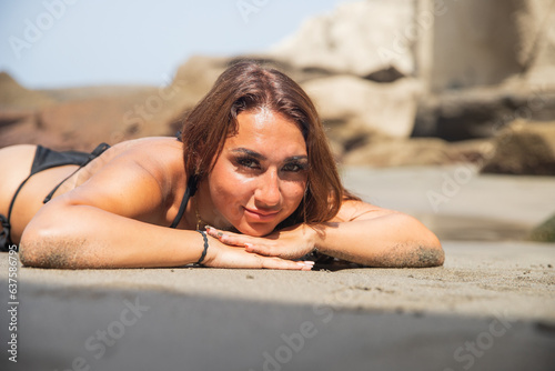 Portrait of an attractive girl lying on the beach in a bikini in summer photo