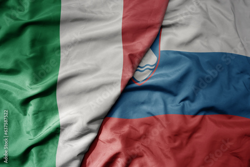 big waving national colorful flag of italy and national flag of slovenia .