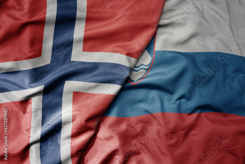 big waving national colorful flag of norway and national flag of slovenia .