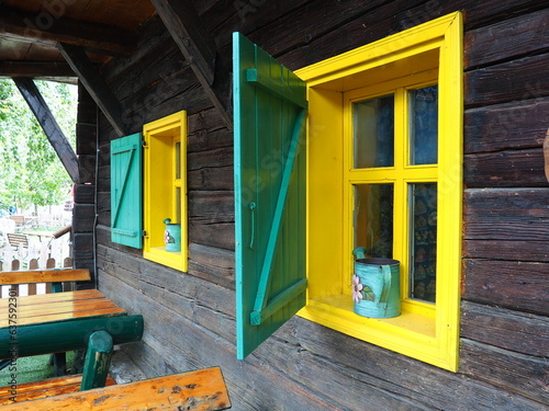 Ethno-folk wooden shutters on a window with a wooden frame, painted green and yellow. Vintage Serbian house, exterior. Architectural complex Stanisici, Bielina, Bosnia and Herzegovina. Log cabin. photo