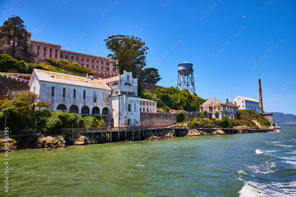 Close up Alcatraz Island with seagull flying overhead and waves against shoreline