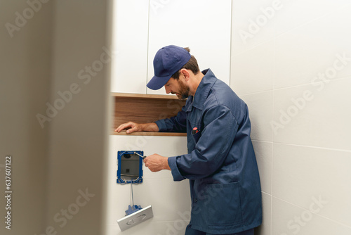 Male plumber holding screwdriver tool while installing toilet flush panel in flat under renovation