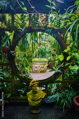 Canvas Print Close up view of moon gate in trellis with statue in front and planter in distan
