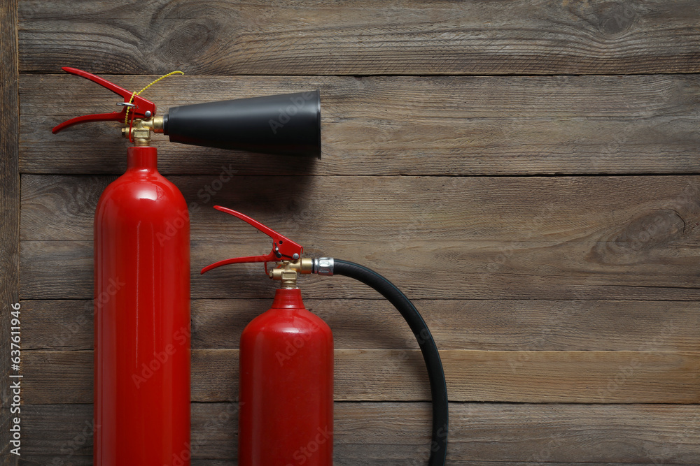 Two fire extinguishers on wooden background, flat lay. Space for text Two fire extinguishers on wooden background, flat lay. Space for text
