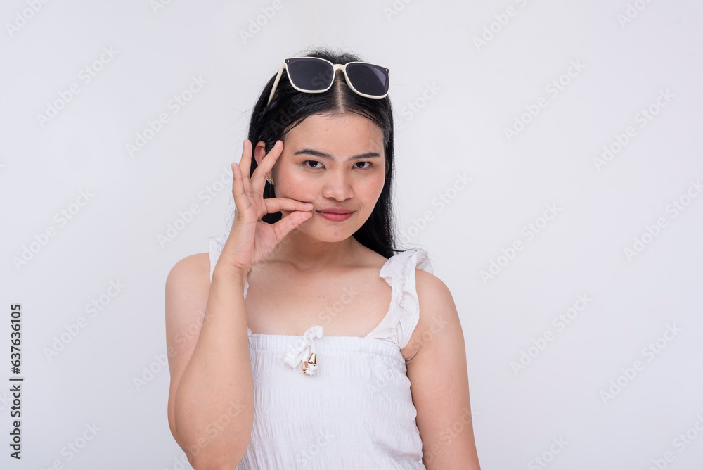 A young asian woman expressing something tiny or little with her thumb and index finger, looking at camera. Describing a small package. Isolated on a white background. A young asian woman expressing something tiny or little with her thumb and index finger, looking at camera. Describing a small package. Isolated on a white background.