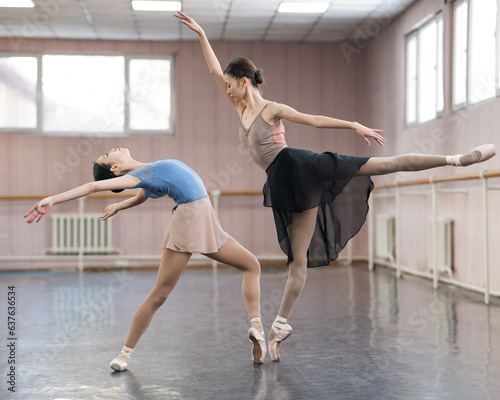 Two Asian ballerinas are dancing in the class. 