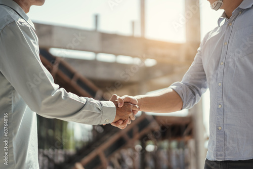 Closeup hand of Architect and engineer construction workers shaking hands while working for teamwork and cooperation concept..