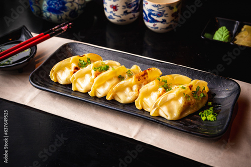 Japanese food | Sushi platter, guioza with soy sauce and chopsticks on a black table. photo