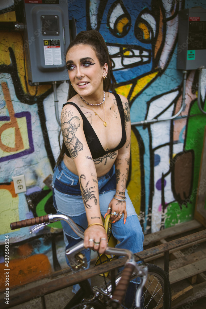 Obraz premium Young beautiful tattooed woman and graffiti street photography