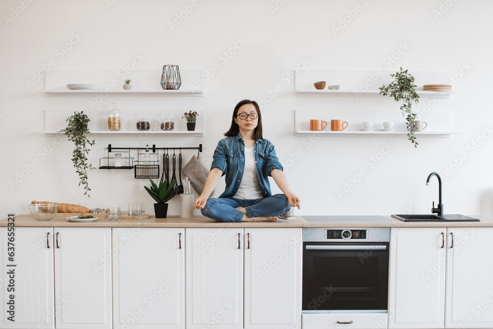 Woman meditating while sitting on white designer kitchen set Woman meditating while sitting on white designer kitchen set