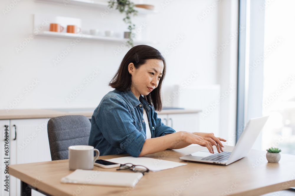 Business lady checking email via computer in kitchen Business lady checking email via computer in kitchen