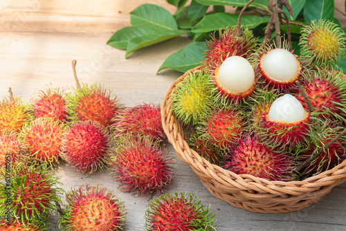 Fresh and ripe rambutans  sweet fruits are placed in baskets and on a wooden floor. Rambutan harvested from the garden.